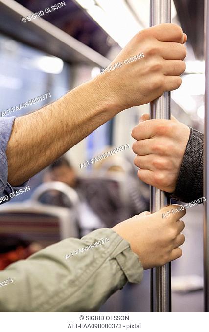 Subway commuters holding onto grab handle