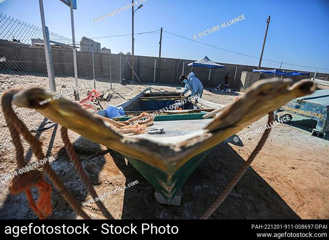 01 December 2022, Palestinian Territories, Gaza City: A Palestinian craftsman repairs a fishing boat using fibreglass at a workshop supervised by the United...