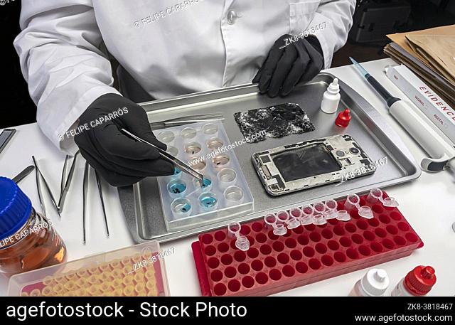 Scientific police extract pieces of burnt smartphone involved in lab murder, concept image