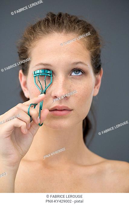 Close-up of a woman curling her eyelashes with eyelash curler