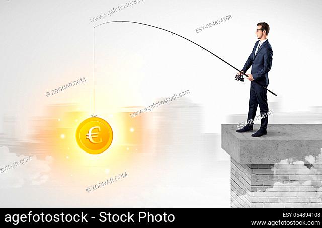 Young businessman fishing coins from a foggy city concept