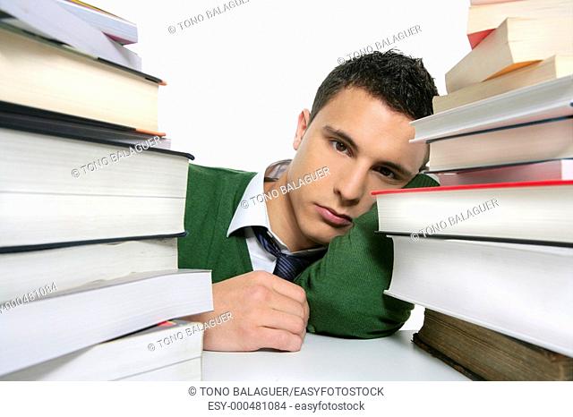 Young unhappy student with much homework and stacked books over white