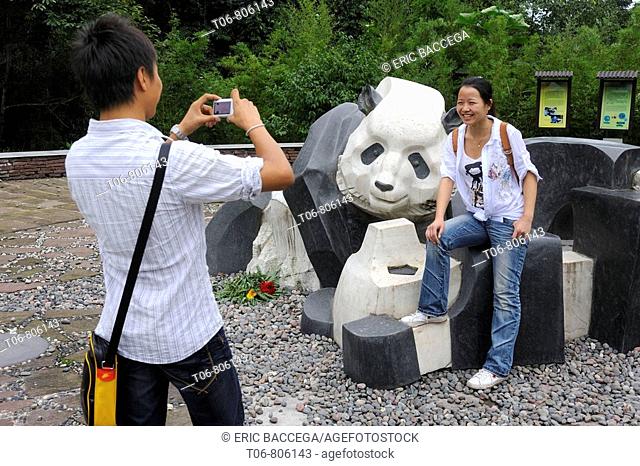 Tourist with giant panda (Ailuropoda melanoleuca) at Bifengxia Giant Panda Breeding and Conservation Center, Yaan, Sichuan, China