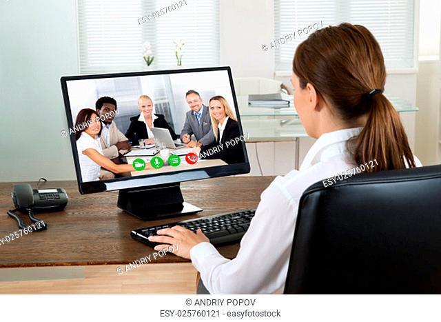 Young Businesswoman Videochatting With Colleagues On Computer In Office