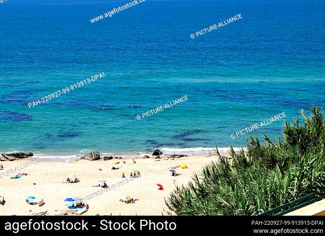 PRODUCTION - 14 August 2022, Portugal, Pataias: Beachgoers sit and lie on the beach ""Praia de Vale Furado"". Photo: Viola Lopes/dpa