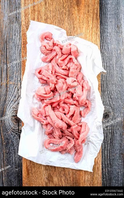 Raw veal strips for traditional Swiss zürcher geschnetzeltes as top view on a wooden cutting board