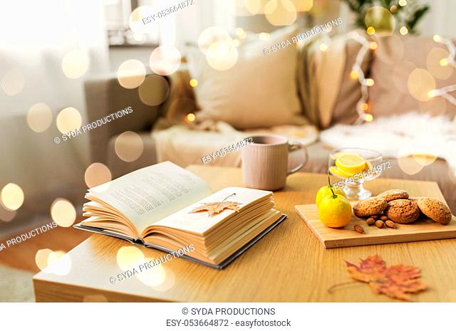 book, lemon, tea and cookies on table at home