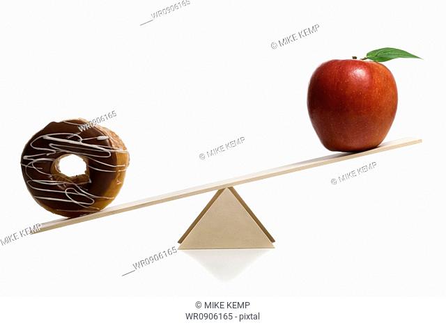 Close-up of a donut and an apple on a seesaw