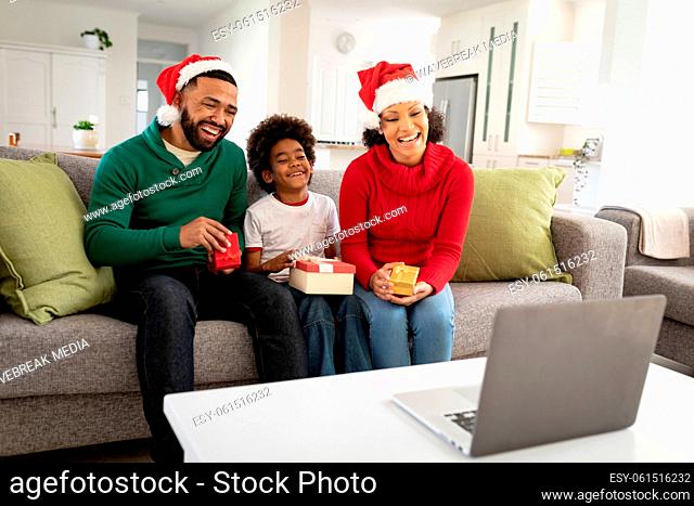 Family in Santa hat waving while having a video chat on laptop at home