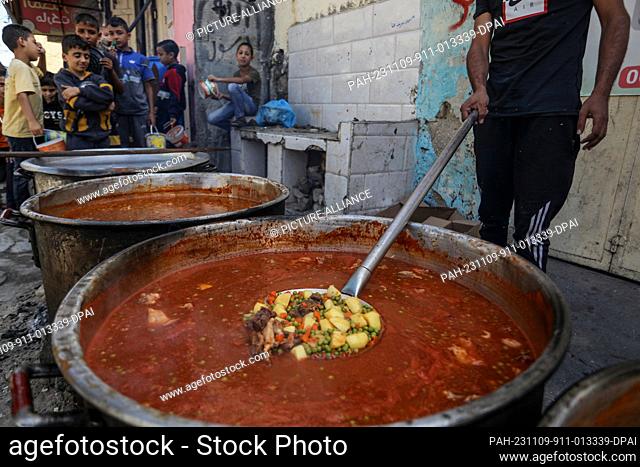 09 November 2023, Palestinian Territories, Rafah: Palestinian volunteers prepare and distribute hot meals to those who were displaced from the northern Gaza...
