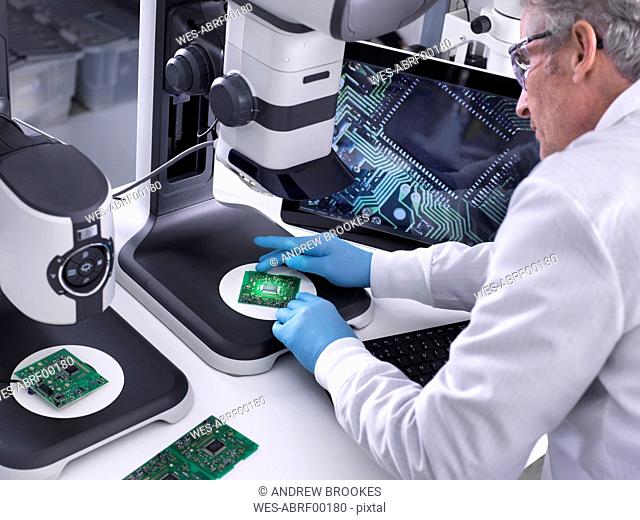Engineer using a 3d stereo microscope for quality control in the manufacturing of circuit boards for the electronics industry