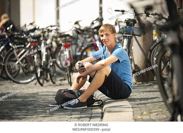 Germany, Munich, Karlsplatz, Young man with mobile, portrait, smiling
