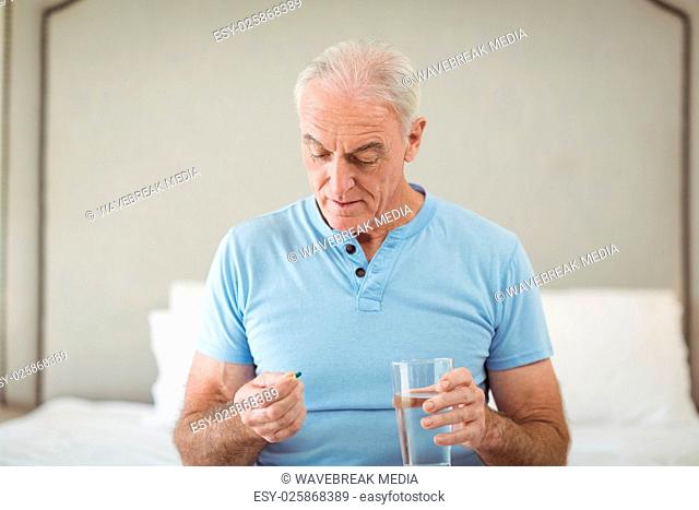 Senior man holding medicine and glass of water