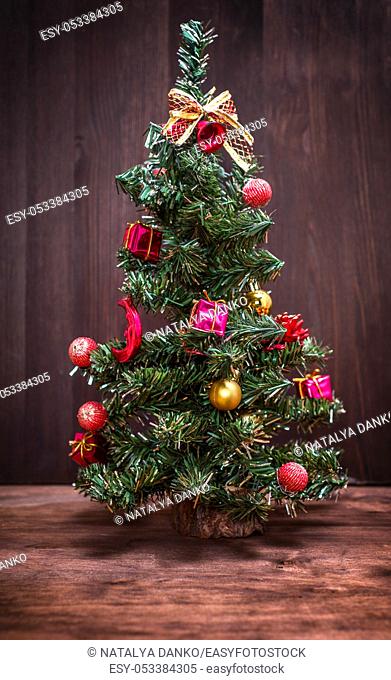Artificial Christmas tree with toys on a brown wooden background