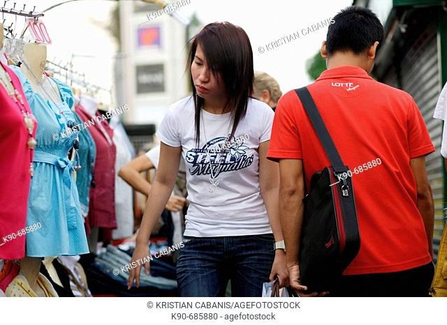 Young Thai woman on Ratchadamri road looking at street stalls which sell clothes close to the Central World shopping mall, City of Angel, Bangkok, Thailand