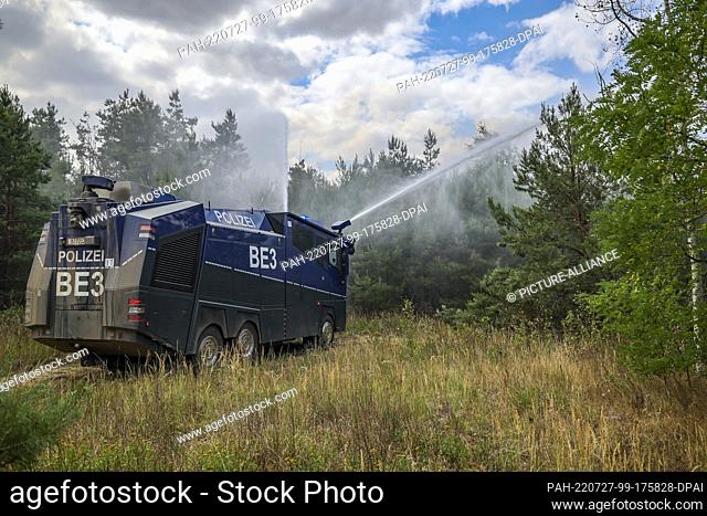 27 July 2022, Brandenburg, Falkenberg: A water cannon of the Brandenburg police extinguishes a forest fire. Firefighters in Brandenburg continue to fight a...