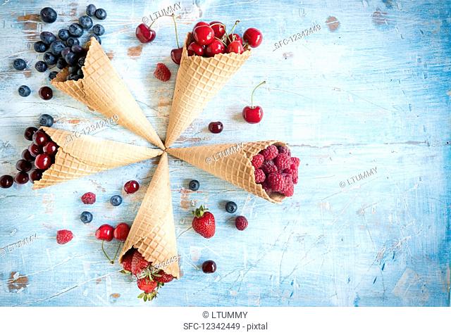 Various berries and cherries in ice cream cones