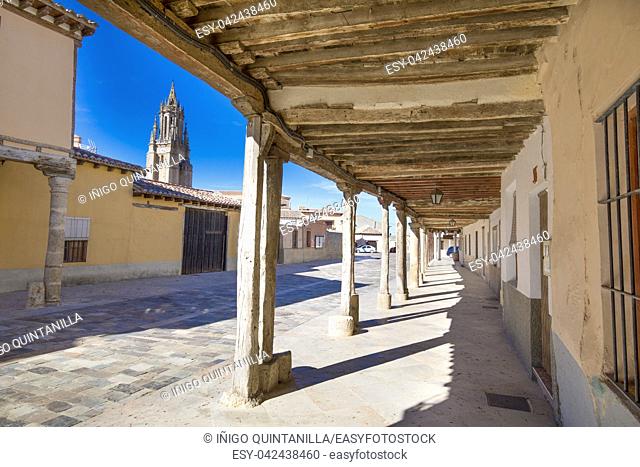 arcaded buildings, in medieval street, landmark and monument from seventeenth century, and church tower, in Ampudia village, Palencia, Castile Leon, Spain