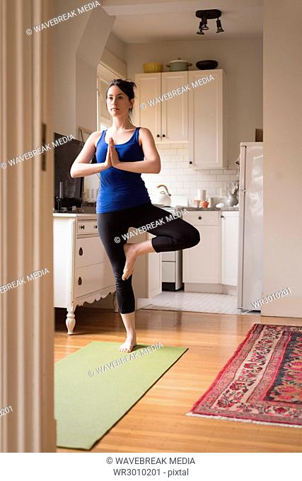 Full length of woman doing yoga in kitchen