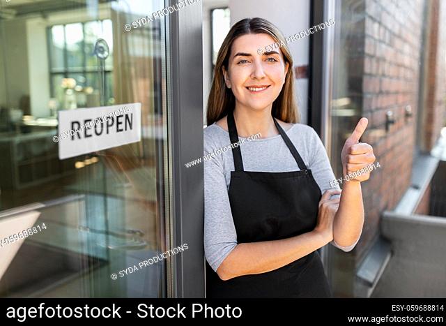 woman with reopen banner on door showing thumbs up