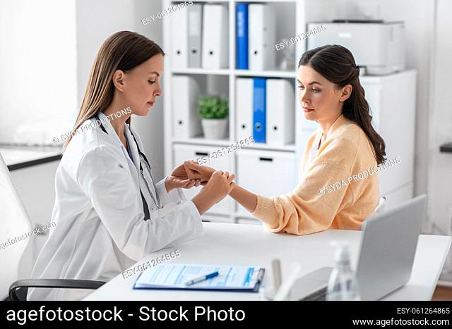 female doctor taking patient's pulse at clinic