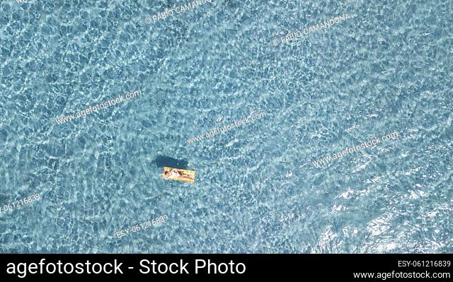 Woman floating on lilo inflatable mattress over blue transparent water surface in summer holiday vacation leisure activity