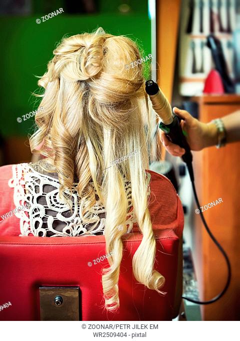The hairdresser does a hairstyle to the bride
