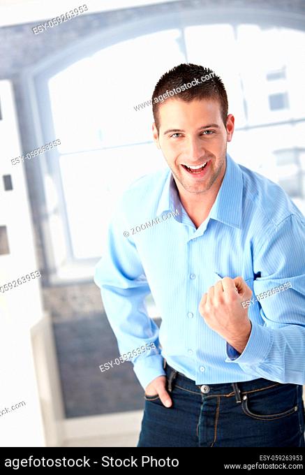 Successful young man celebrating with clenched fist, smiling happily