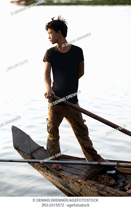 Portrait of a young fisherman at work on the Mekong River early in the morning outside of Phnom Penh, Cambodia