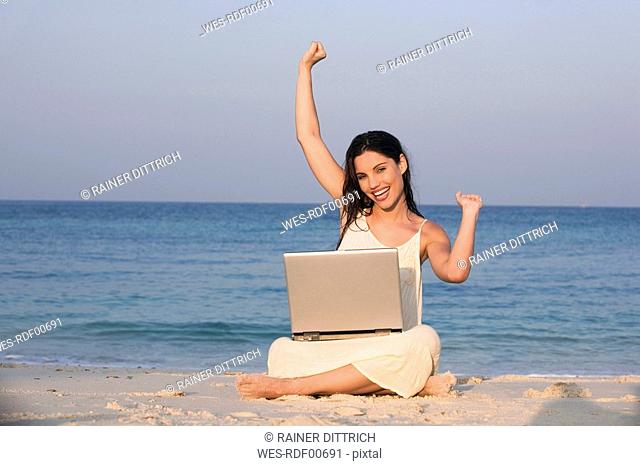 Asia, Thailand, Young woman using laptop on beach, portrait