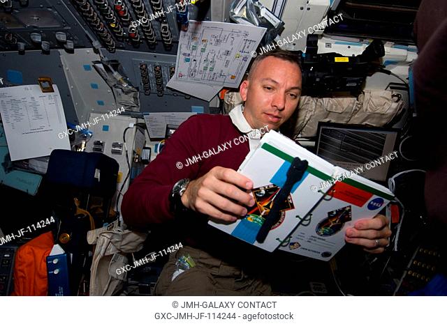 Astronaut Randy Bresnik, STS-129 mission specialist, reads his crew notebook on the aft flight deck of Space Shuttle Atlantis during flight day two activities