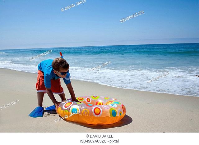 Young boy pushing rubber ring on beach