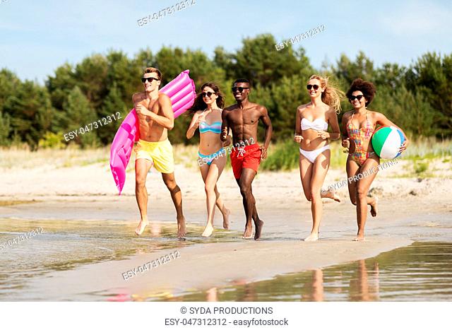 friends run with beach ball and swimming mattress