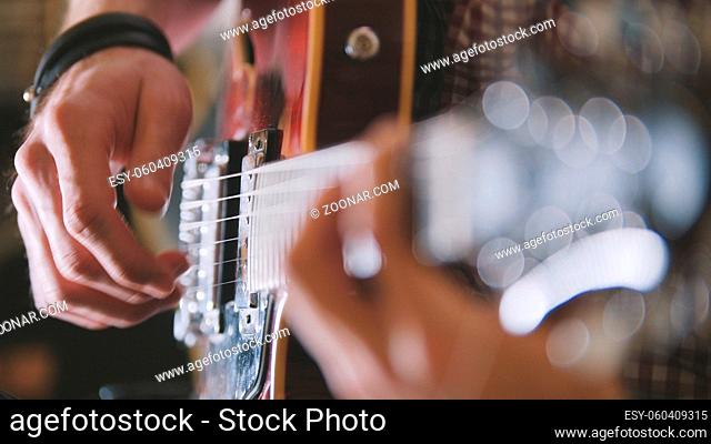 Male musician plays the guitar, hands close up, focus on the guitar fretboard, art concept