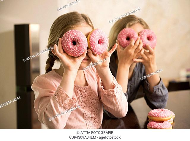 Portrait of two sisters with doughnut holes over their eyes
