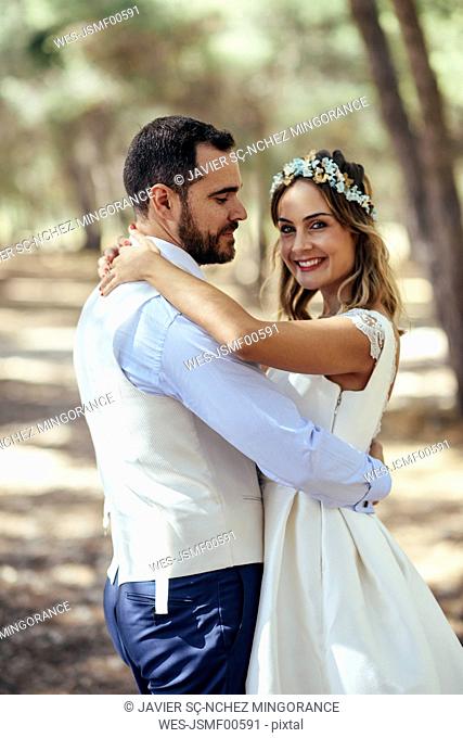Portrait of happy bride dancing with her groom in pine forest