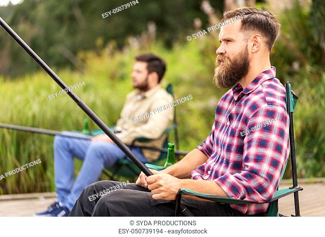 male friends with fishing rods on lake