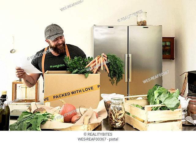 Mature man with delivery service packing organic vegetables in cardboard