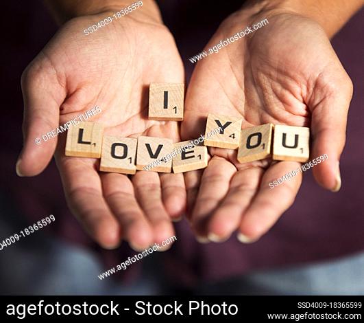 Detail shot of woman holding loose scrabble pieces with the phrase ?I Love You? spelled out on the little wooden blocks. Love
