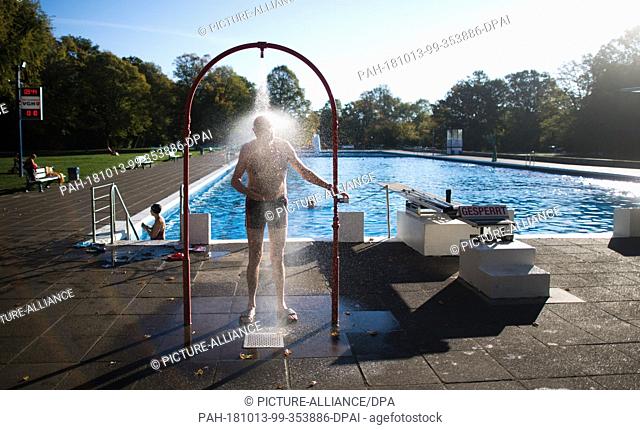 13 October 2018, Lower Saxony, Hannover: A pool guest taking a shower in the Annabad outdoor pool. The open-air swimming pool remains open after the official...