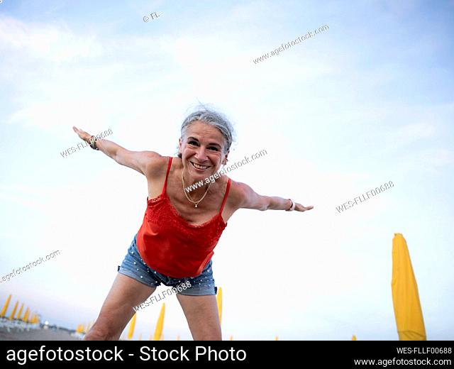 Smiling senior woman doing gymnastics at beach