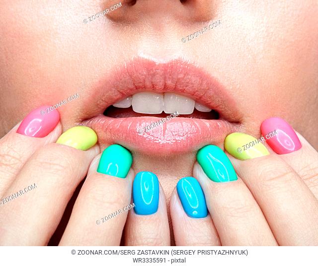 Closeup shot of young blonde woman with fun varicoloured finger nails manicure