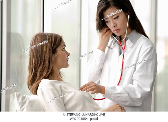 Female doctor checking patient's heart with stethoscope