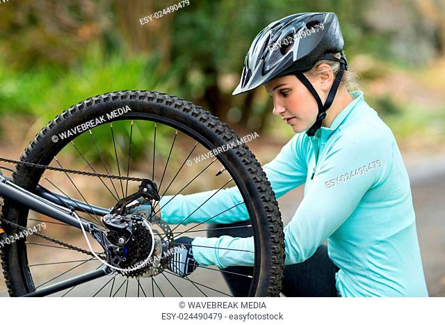 Fit woman fixing the chain on her bike