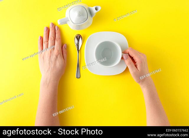 Woman hand with perfect white cup isolated on yellow background
