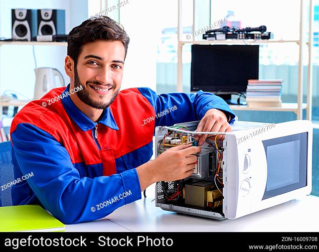 The young repairman fixing and repairing microwave oven