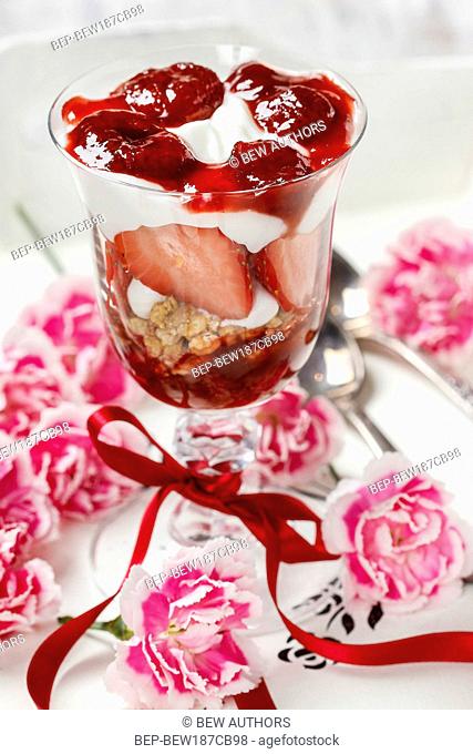 Layer strawberry and muesli dessert in glass goblet. Selective focus