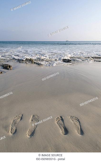 Two people's footprints on sand