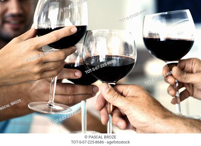 Close-up of four people's hands toasting with red wine