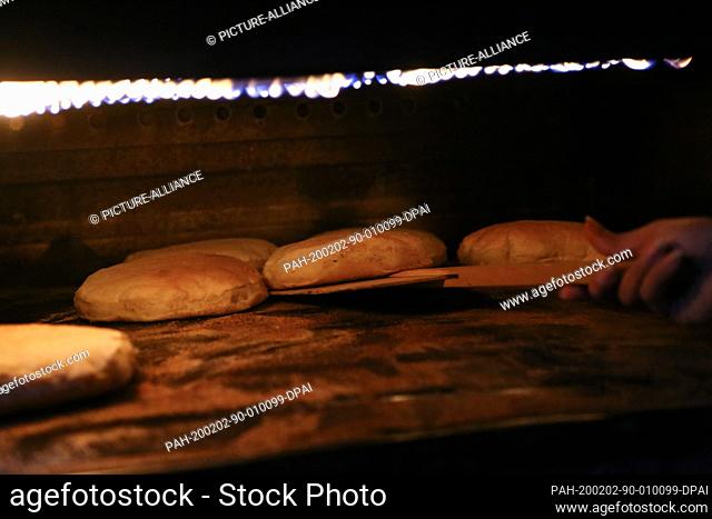 29 January 2020, Egypt, Manfalut: A picture provided on 02 February 2020 shows a woman removing from the oven Sun Bread, known in local dialect as ""Eish...